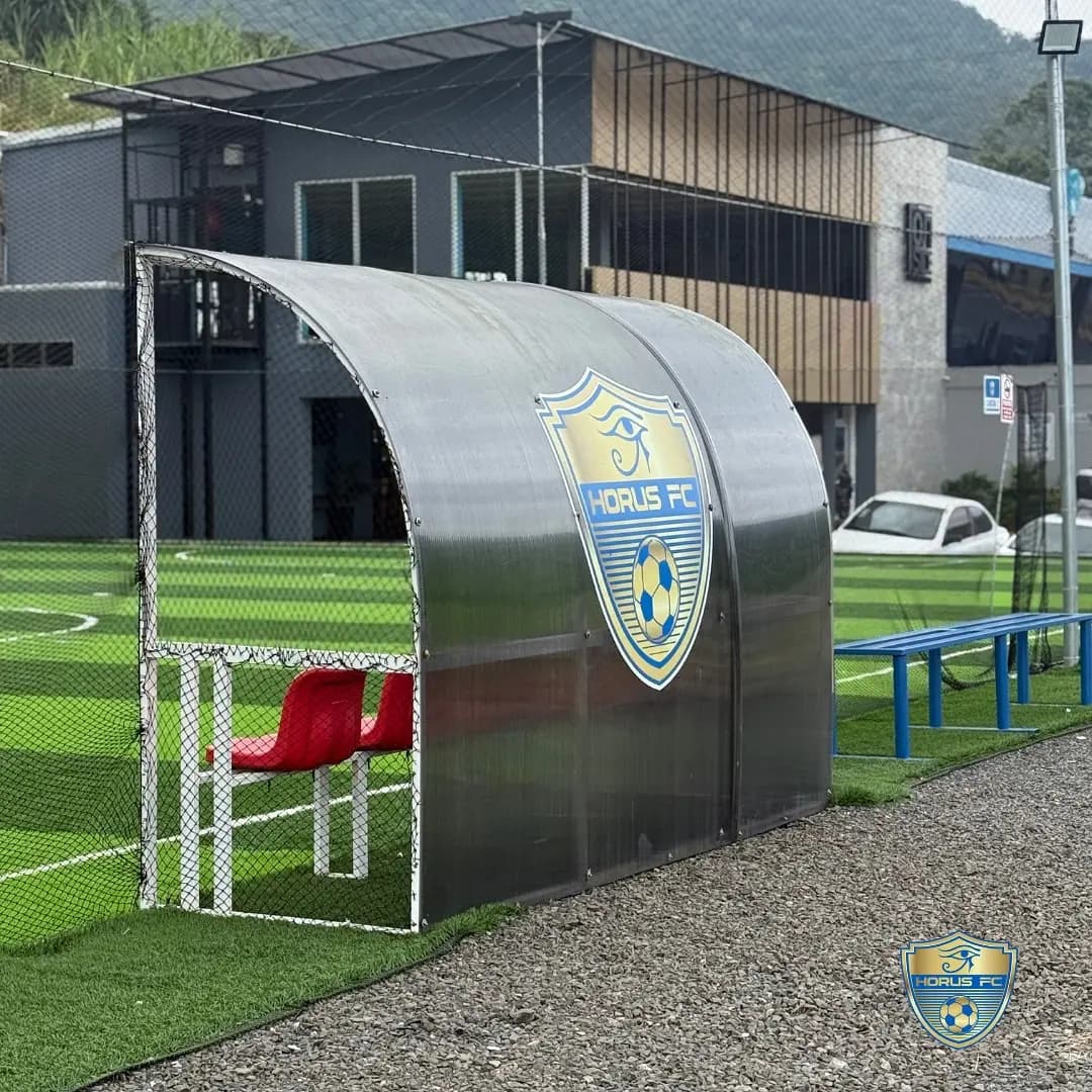 Banquillos para jugadores y cuerpo técnico junto al terreno de juego.